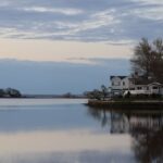 Peaceful twilight scene of lakeside houses reflecting on calm water in Stamford, Connecticut.