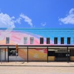 Bright mural on a building facade under clear blue skies in Houston, Texas.