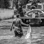 A black and white photo depicting flood cleanup efforts in an urban setting, showcasing resilience.