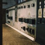 Vintage industrial control panel with warning signs in a dimly lit room, creating a moody atmosphere.