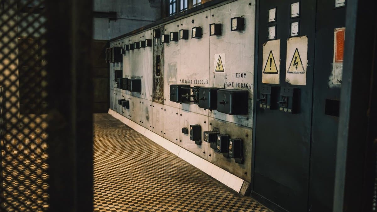 Vintage industrial control panel with warning signs in a dimly lit room, creating a moody atmosphere.