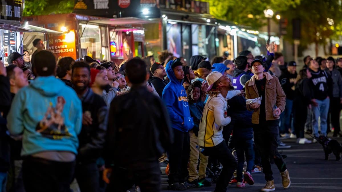 A lively crowd gathers around vibrant food trucks at night, enjoying a bustling street food experience.