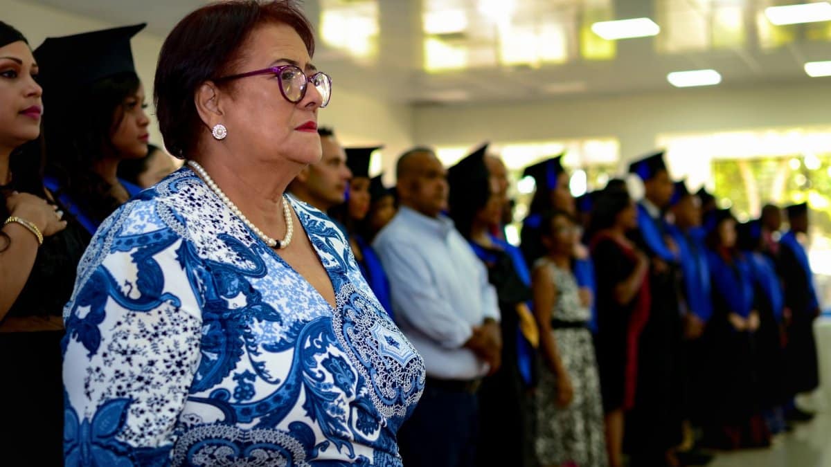 Graduation ceremony with guests and graduates in caps and gowns indoors.