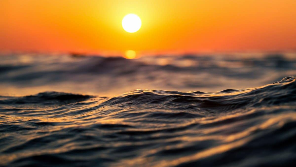 Close-up of ocean waves at sunset with warm orange tones, capturing serenity and nature's beauty.