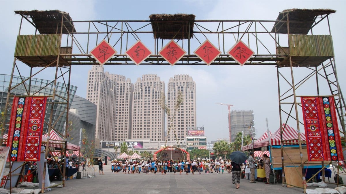 Vibrant outdoor cultural festival with decorated entrance, tents, and lively crowd.