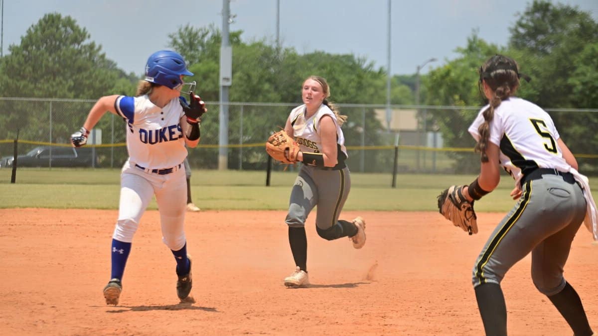 Players engage in a competitive softball game under a clear blue sky, showcasing teamwork and sportsmanship.