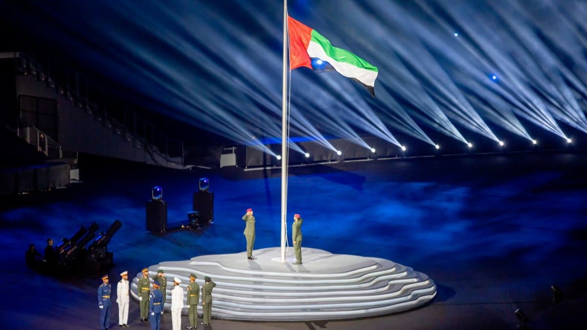 Military personnel saluting the raised UAE flag during an official ceremony.