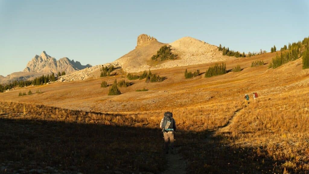 Backpackers hiking the dramatic Teton Crest Trail during autumn in Wyoming, USA.