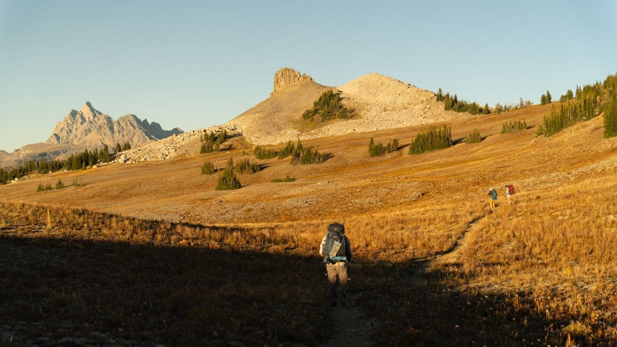 Backpackers hiking the dramatic Teton Crest Trail during autumn in Wyoming, USA.