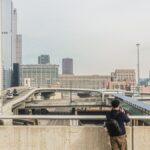 A man photographs the urban cityscape and highway of downtown Chicago, capturing skyscrapers and modern architecture.