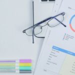 A modern workspace featuring budget graph, laptop, glasses, and stationery for creative business planning.