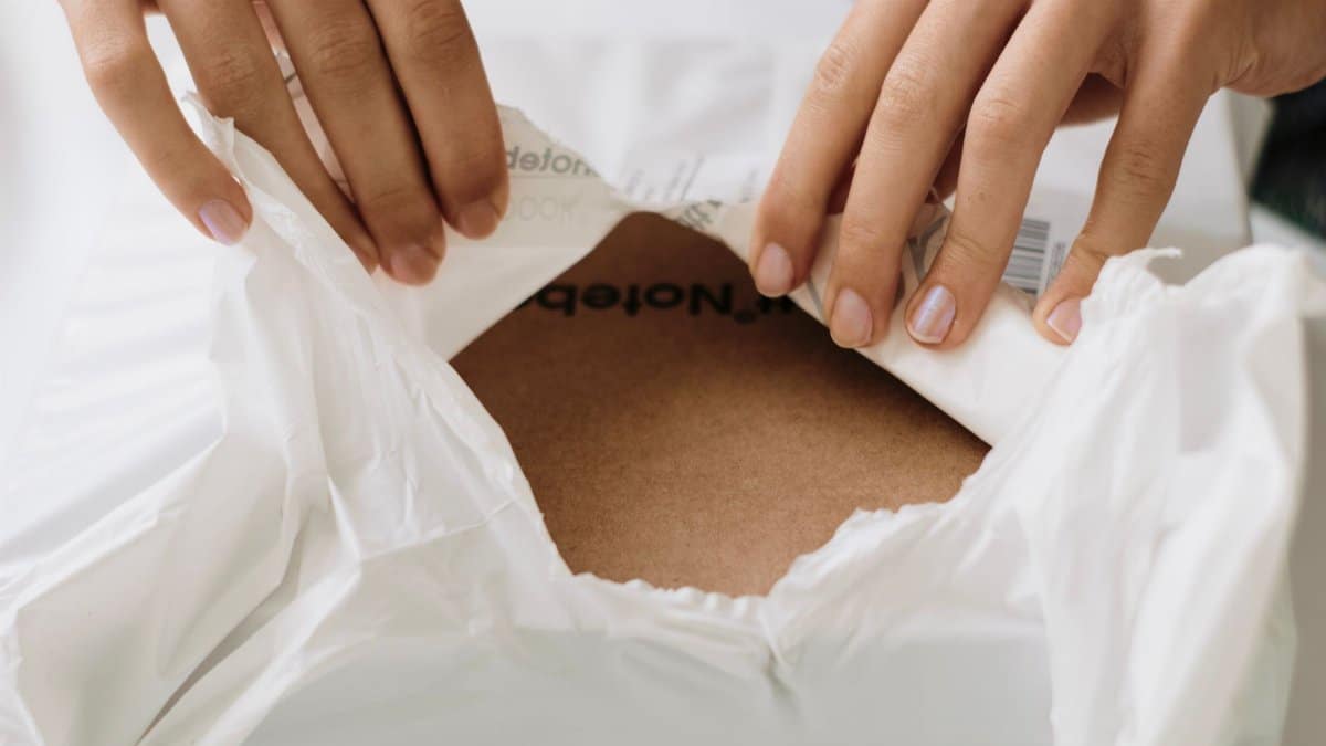Hands carefully opening a white package to reveal contents inside. Perfect for unboxing themes.