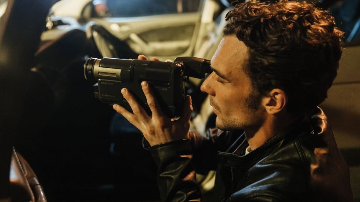 A man uses a camera inside a car during nighttime, possibly capturing footage for an investigation.