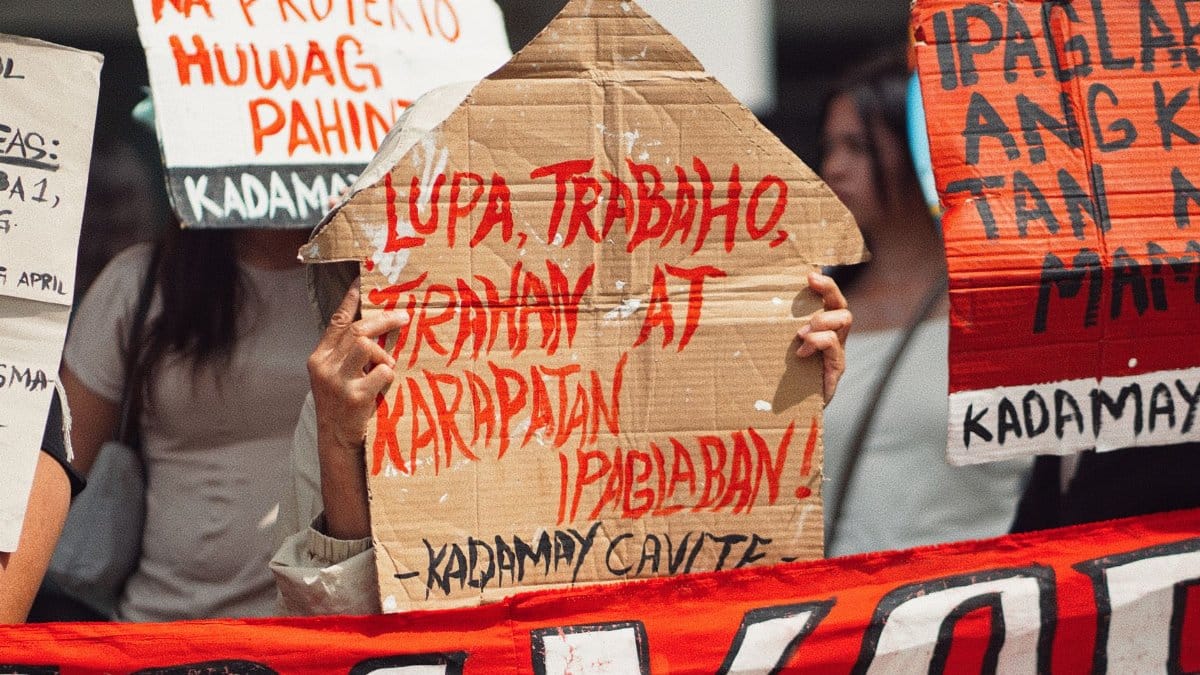 People holding handmade cardboard signs advocating for labor rights during a protest.