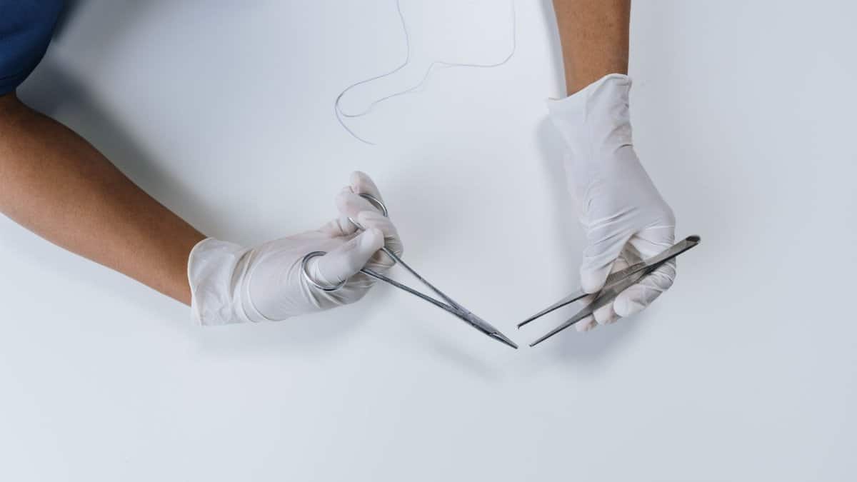 Overhead shot of a medical professional's hands holding surgical instruments with gloves.