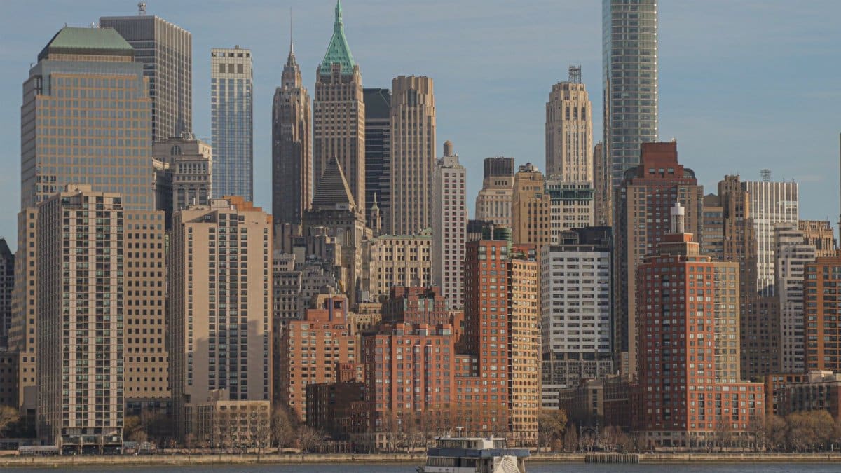 Stunning view of New York City's iconic skyline featuring skyscrapers and a ferry on the Hudson River.