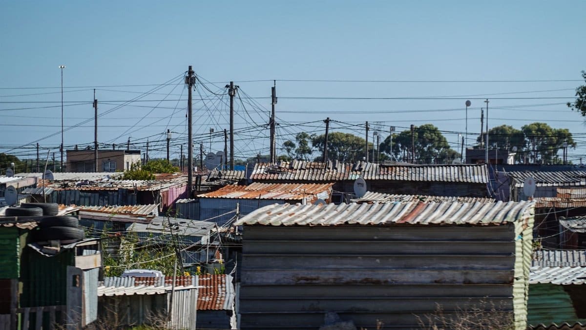 Aerial perspective of corrugated iron roofs in an urban informal settlement under a clear sky.