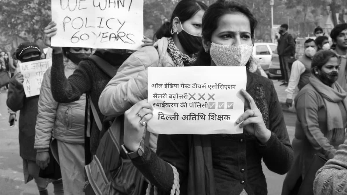 Grayscale image of a protest with people holding placards demanding policy change.
