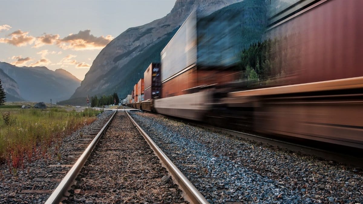Vivid image of a freight train on tracks beneath majestic mountains in Field, BC.