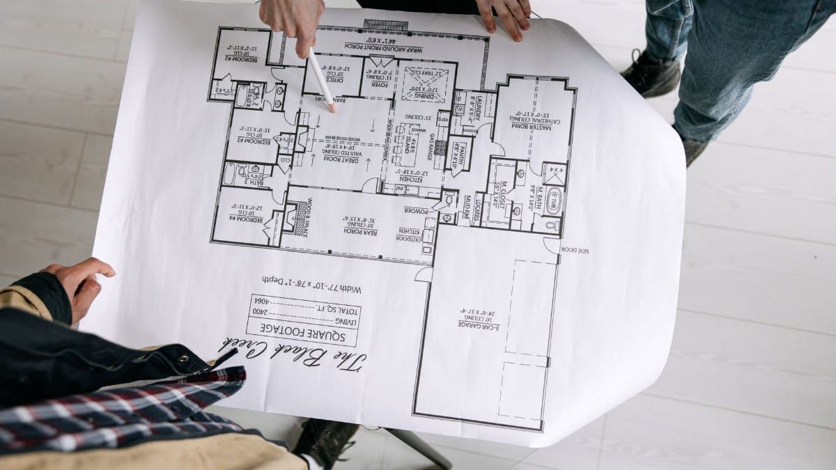 Two architects examining a detailed floor plan blueprint on a table indoors.