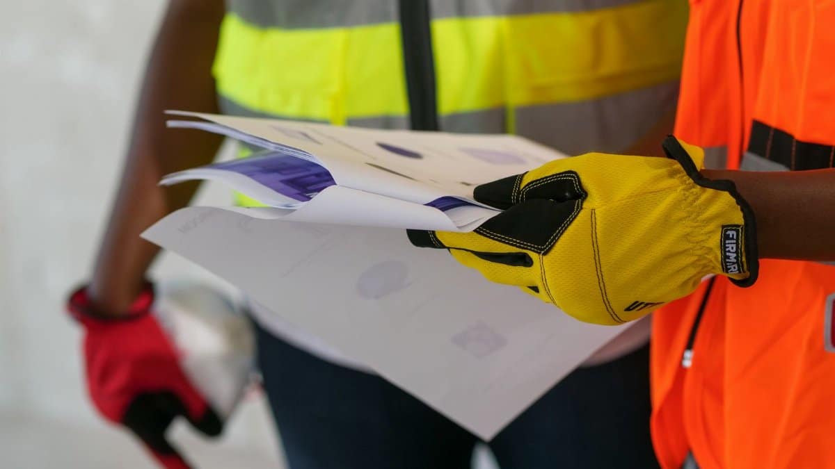 Close-up of construction workers reviewing documents wearing protective gear. Safety-focused interaction.