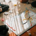 Kids enjoy a tabletop board game with map-based gameplay, cards, and tokens indoors.