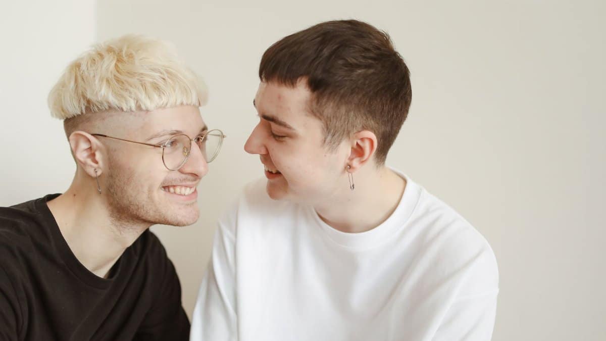A happy same-sex couple gazing at each other, depicting love and happiness indoors.