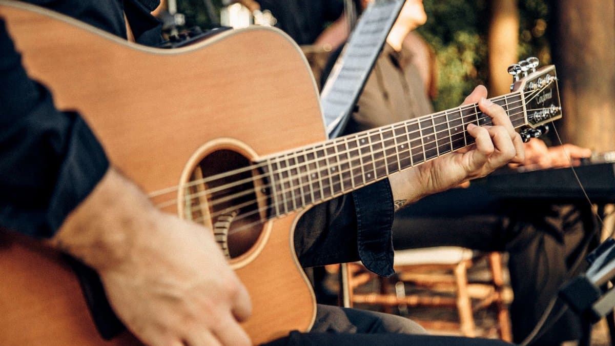 Close-up of a man playing an acoustic guitar at an outdoor concert, capturing the essence of live music.