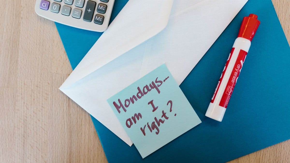 Flat lay image of office supplies including envelope, marker, and a playful Monday note.