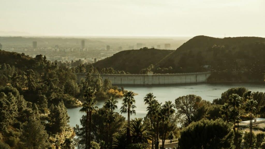 Amazing scenery of Hollywood Reservoir and dam amidst green verdant trees and hills in California on sunny day