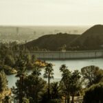 Amazing scenery of Hollywood Reservoir and dam amidst green verdant trees and hills in California on sunny day