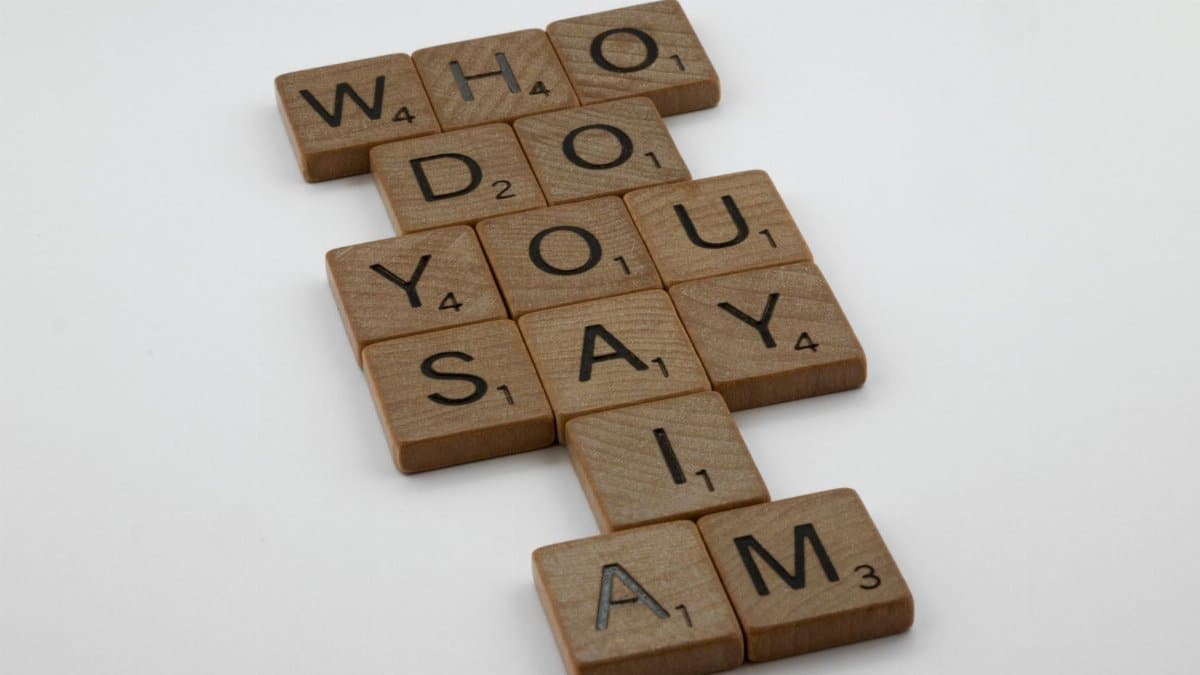 Wooden scrabble tiles arranged to spell 'Who do you say I am' on a white background.