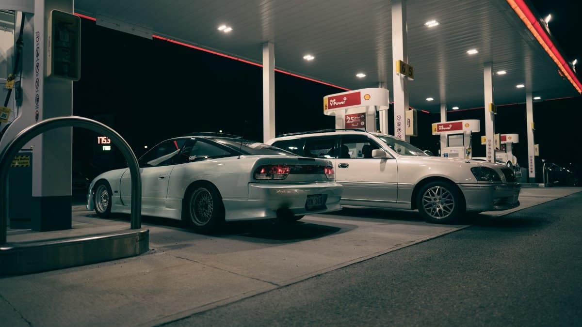 Two cars parked at a gas station during nighttime, showcasing urban travel vibes.