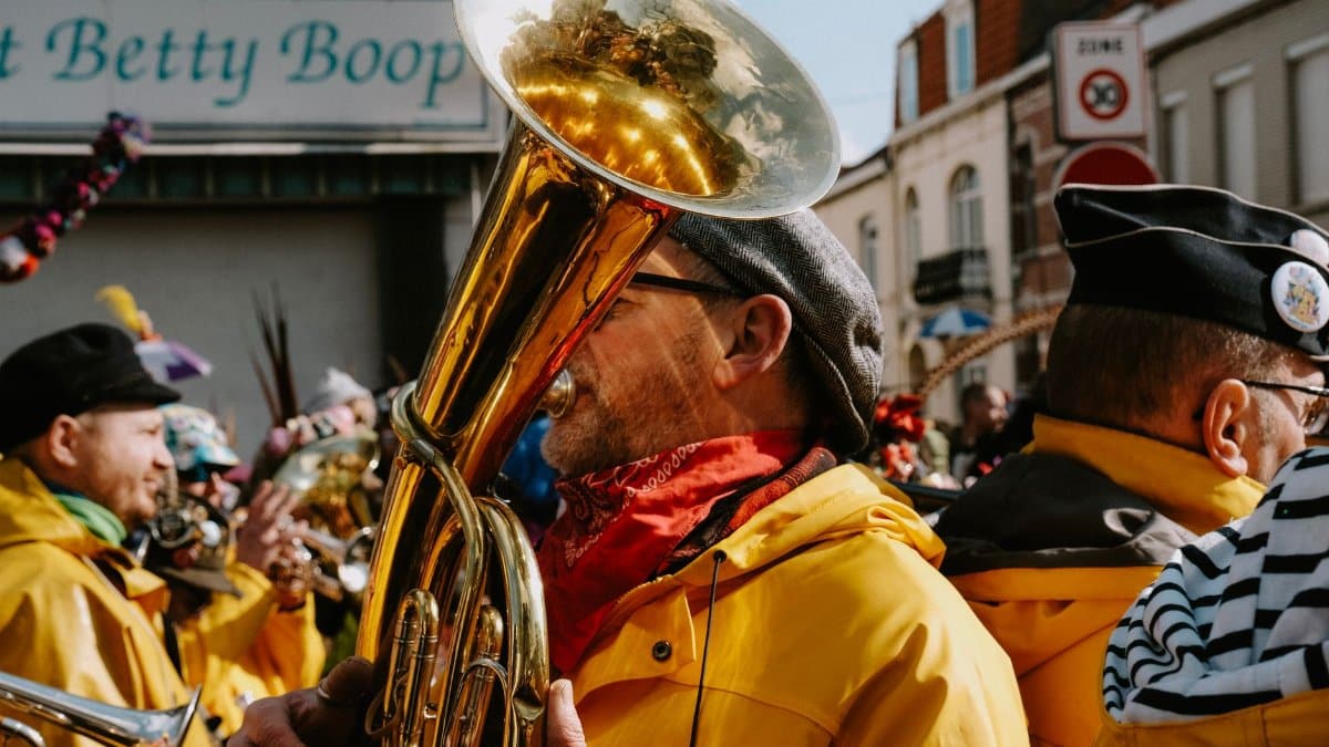 Colorful street parade featuring musicians in vibrant costumes playing brass instruments.