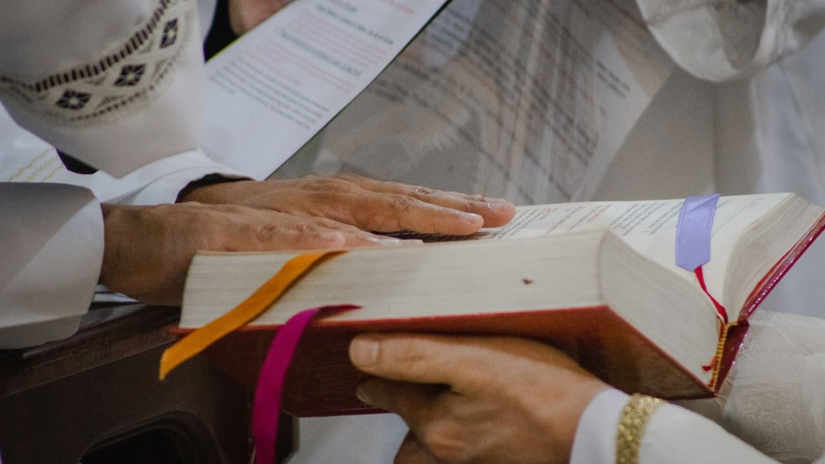 Priest during a sacred ceremony holding a holy book with ribbons. A spiritual moment captured indoors.