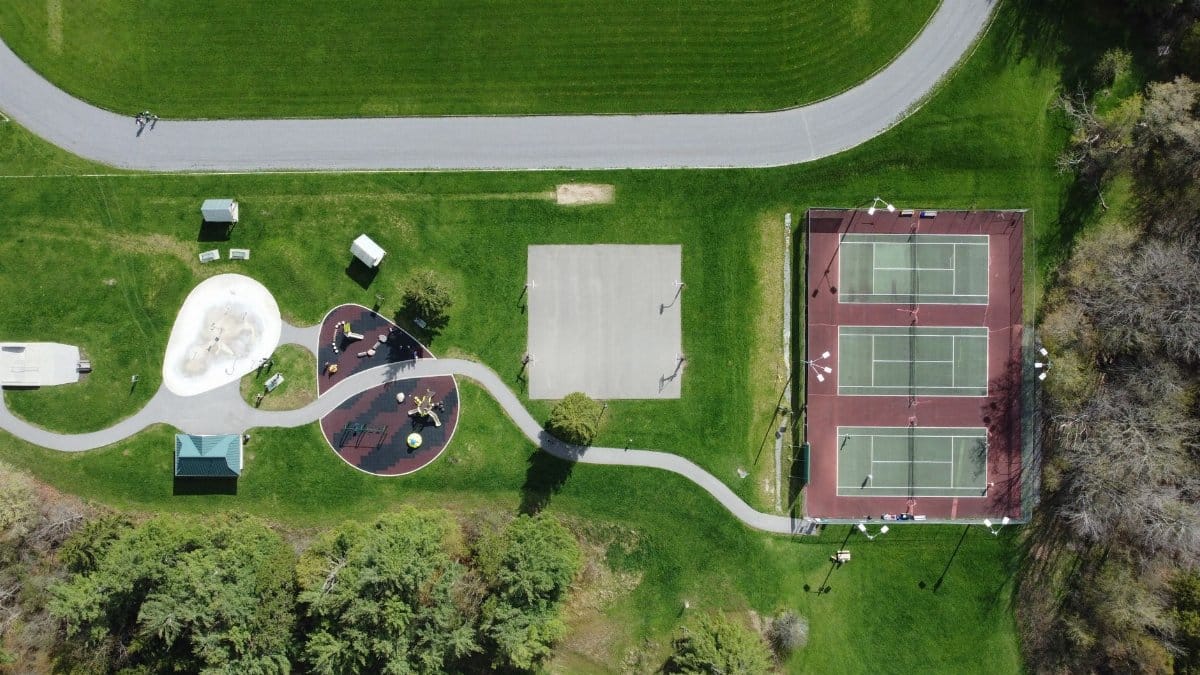 Aerial shot of a park with playground, tennis courts, and greenery in Mississippi Mills, Canada.