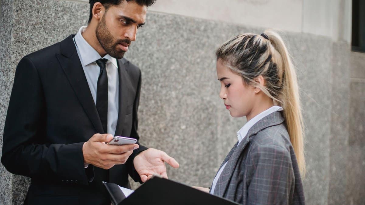 Two business professionals engaging in a serious conversation outside a building.