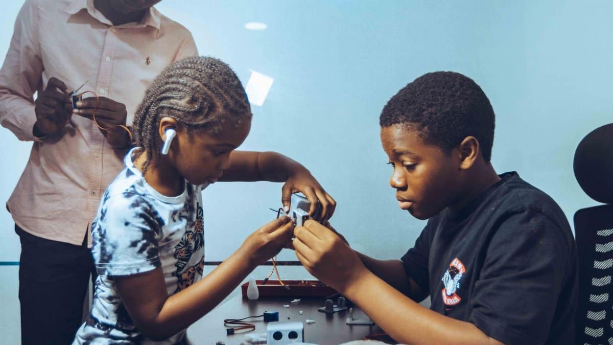 Children collaborating on electronics project in a workshop, fostering STEM education and teamwork.