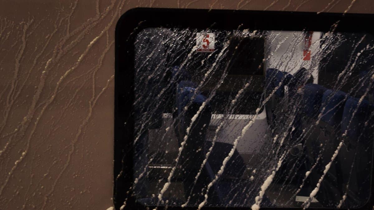 Close-up of a rain-soaked train window capturing interior reflections on a journey.