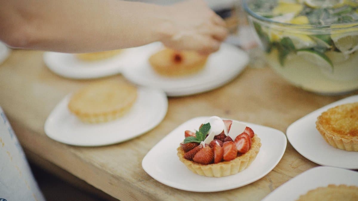 Close-up of a strawberry tart being served, showcasing fresh ingredients and garnishing.