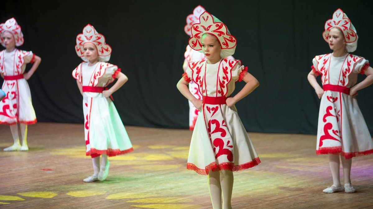Young girls in traditional attire performing a cultural dance on stage.