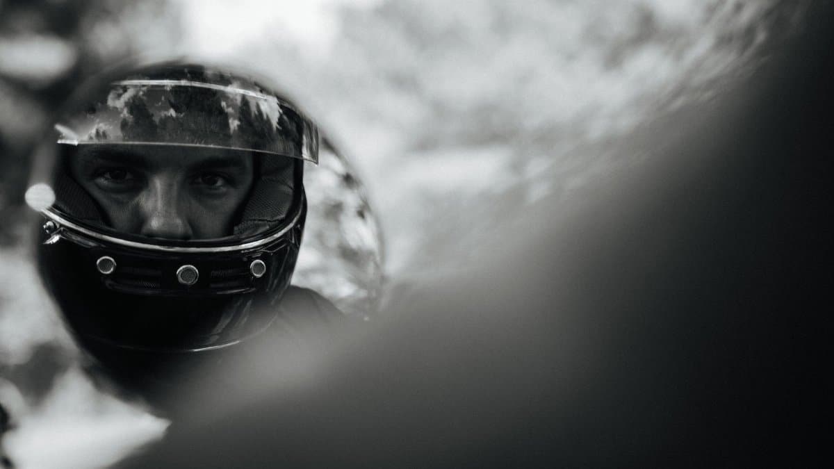 An intriguing black and white reflection of a man wearing a helmet, captured in a mirror.