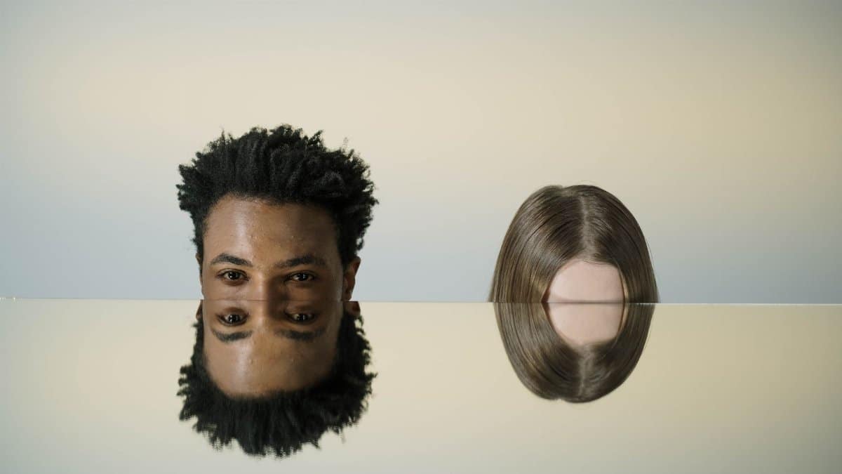 Artistic mirror portrait showing two heads with creative reflections, combining abstract elements and human interaction.