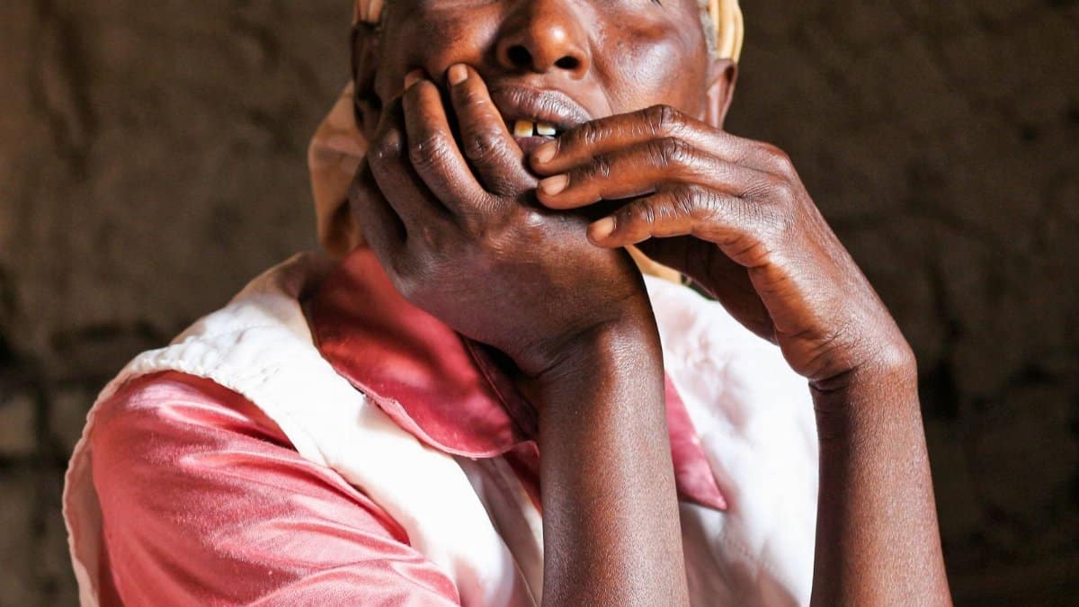 Portrait of an African woman in reflective thought, hands on face.
