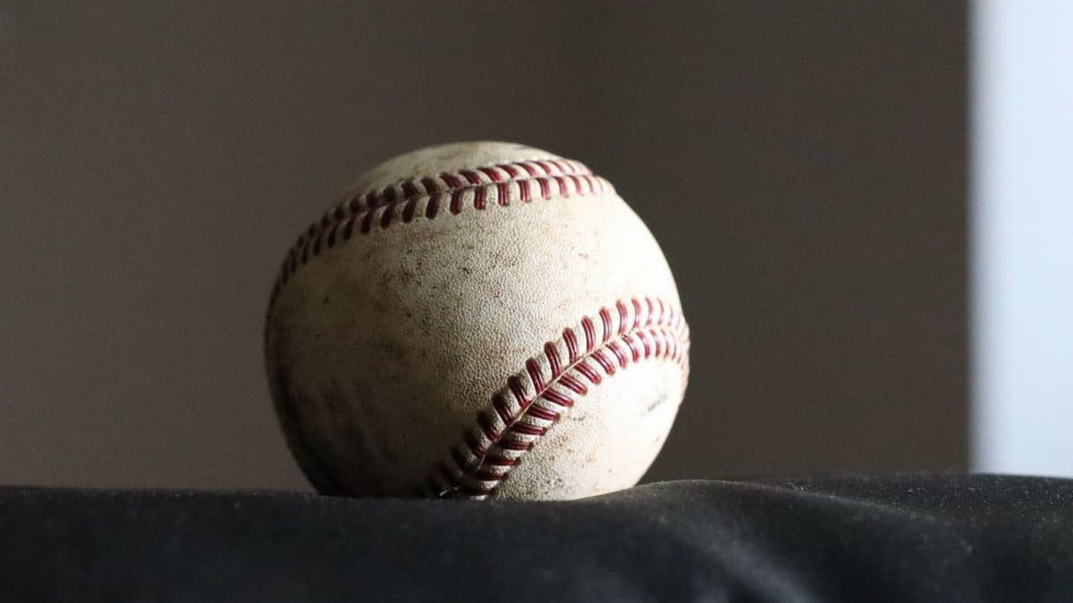 High-resolution image of a worn baseball on a dark surface, highlighting its stitching and texture.
