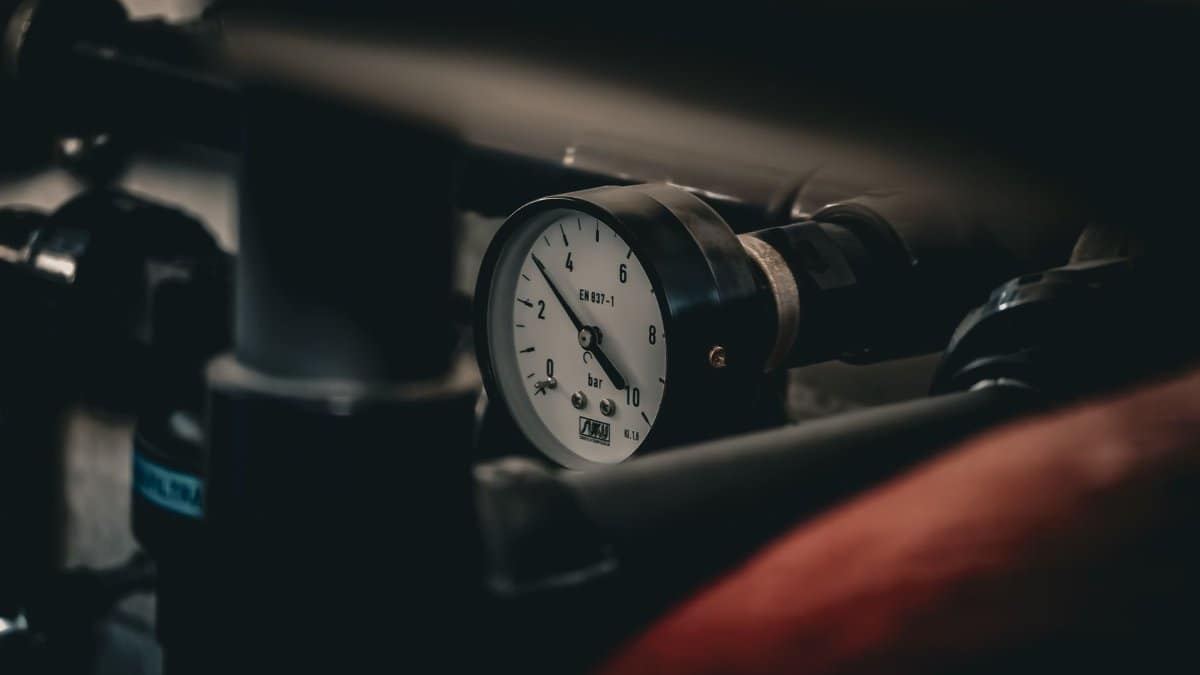 Close-up of a pressure gauge on an industrial pipe system, displaying measurements in bar.