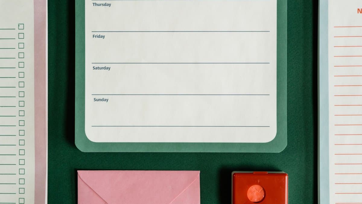 Flat lay of assorted stationery on a green surface, emphasizing organization.