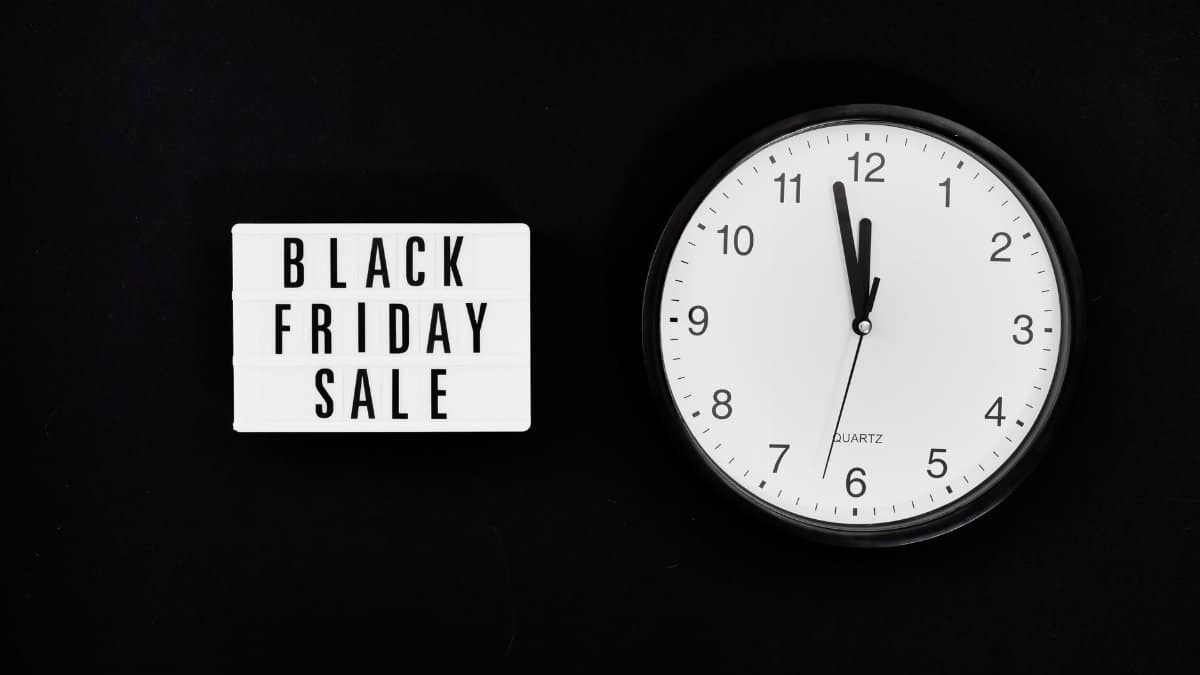 Minimalist clock with a Black Friday sale sign on black background, highlighting a midnight sale countdown.