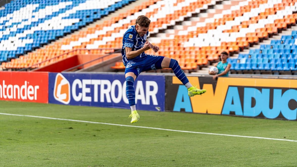 Soccer player in mid-air jump during game in vibrant stadium setting.