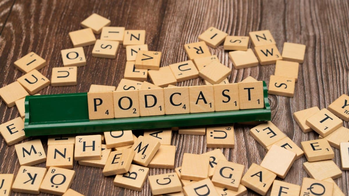 Wooden letter tiles on a board spelling the word 'Podcast', symbolizing digital media and creativity.